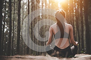 Back view of beautiful woman doing yoga pose in peaceful natural forest. Lifestyle and Meditation concept. Healthy and Mental