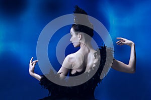 Back view of beautiful woman, flexible ballerina in black ballet outfit, tutu dancing at blue studio full of light.