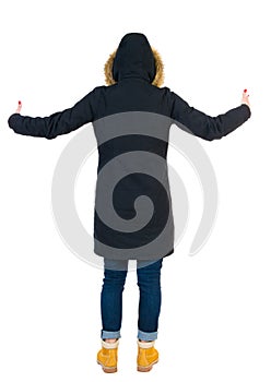 Back view of Beautiful woman in parka looking at wall and Holds