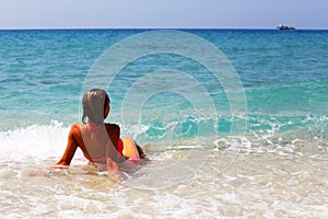 Back view of beautiful woman sitting on the beach