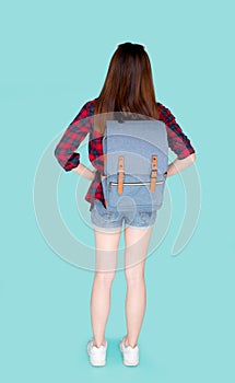Back view of beautiful young asian woman travel with backpack  on blue background