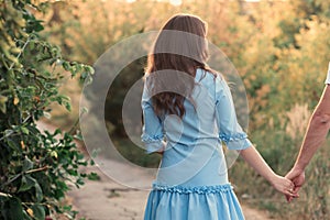 Back view of a beautiful young woman or girl on very green meadow watching the sunset