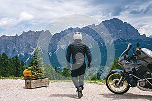 Back view of biker in center. Adventure touring motorcycle in full equipment on dirt road,