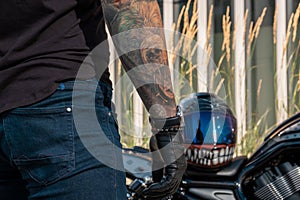 Back view of biker standing next to his motorcycle with helmet on bike\'s seat