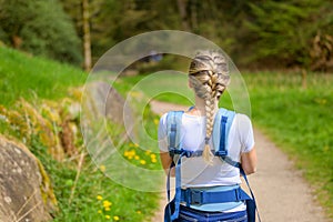 Back view of a blonde woman walking through a park with her little baby photo