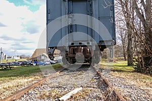 Back view of a blue railroad car on tracks. The car coupler mechanism and undercarriage are rusted.
