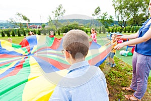The back view of a boy with large parachute in his hands