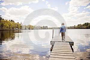 Back view of boy walking on dock in lake