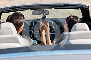 Back view of boyfriend and girlfriend cheering with coke bottles driving cabriolet