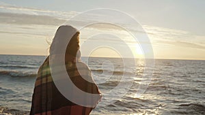 Back view of the brunette woman standing on the shore of sea and dreaming. Young female enjoying the beach and sunset.