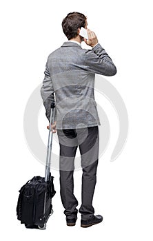 Back view of business man with suitcase talking on the phone