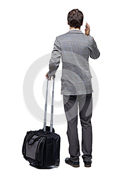 Back view of business man with suitcase talking on the phone