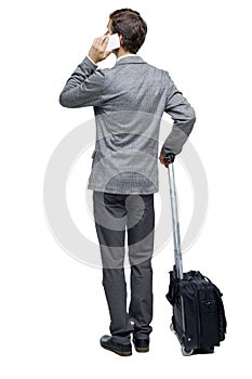 Back view of business man with suitcase talking on the phone