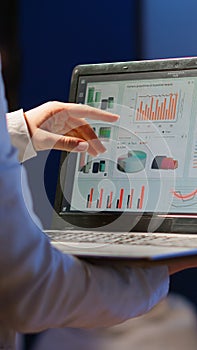 Back view of business woman analysing financial statistics holding laptop