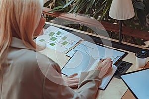 Back view of business woman working with documents and making notes while sitting the desk