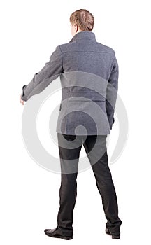Back view of businessman in coat reaches out to shake hands.