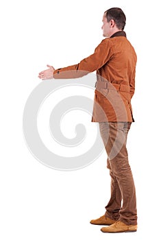 Back view of businessman in movement reaches out to shake hands