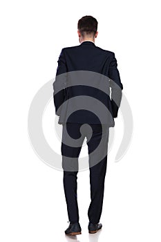 Back view of businessman standing with hands in pockets