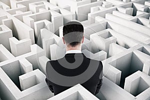 Back view of businessman in suit looking at maze. Solution and challenege concept