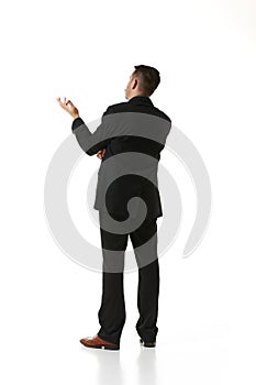 Back view. Businessman in a suit standing, thinking, considering ideas over white studio background. Concept of business