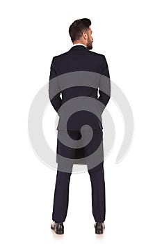 Back view of a businessman with suitcase looking to side