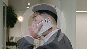 Back view businessman walk in hallway office talk mobile phone. Turn head behind Asian chinese korean man executive