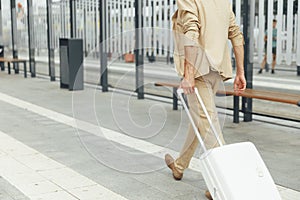 Back view of businessman walking at bus stop with suitcase