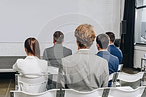 back view of businesspeople sitting on chairs at training