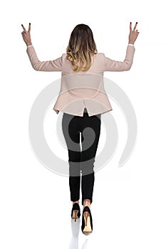 Back view of businesswoman celebrating and making peace sign