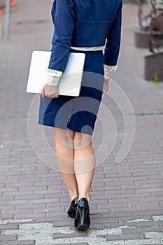 Back view of businesswoman holding note book and goes along the road