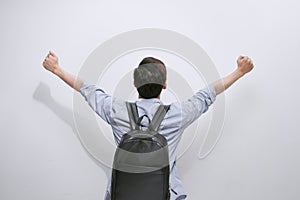 Back view of a casual man celebrating success with hands in the air on white background