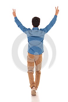 Back view of a casual man celebrating victory and walking