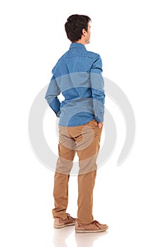 Back view of a casual man with hands in pockets