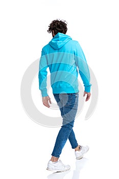Back view of casual model in hoodie looking to side and walking