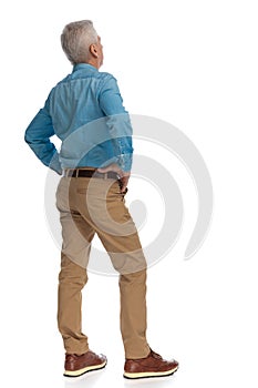 Back view of casual old guy in denim shirt with chino pants holding hands