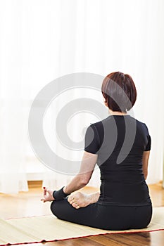 Back View of Caucasian Brunette Woman Practicing Yoga Indoors. Doing Sukhasana Exercises In Physical Lotus Therapy Pose.In Front