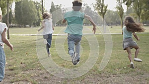 Back view of cheerful kids competing in speed on nature in park