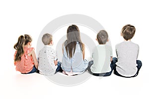 Back view of child group sitting on floor looking at wall