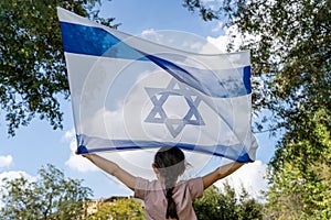 Back View On Child Holding Israeli Flag High.