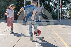 Back view of child kicking soccer ball. Grandfather soccer goalkeeper warding the football goal.