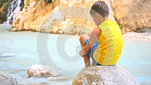 Back view of child sitting on stone