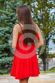 Back view close up portrait young beautiful brunette woman in red dress