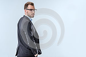 back view of confident businessman in eyeglasses and formal wear looking at camera