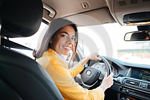 Back view of a confident smiling woman driving car