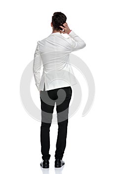 Back view of a confused business man scratching his head