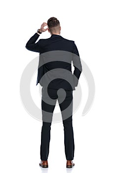 Back view of confused businessman scratching his head