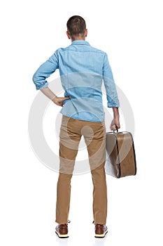 Back view of confused young man holding baggage while leaving in a trip around the world