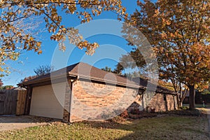 Back view of corner house with attached garage and yard in fall season suburbs Dallas