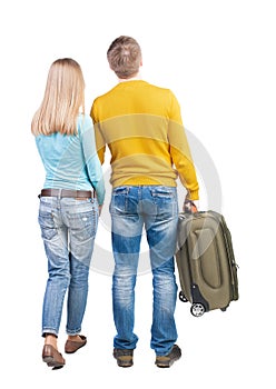 Back view of couple with green suitcase looking up.