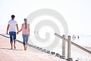 Back view, couple holding hands and walk on beach, romantic date and commitment with trust. Love, care and people
